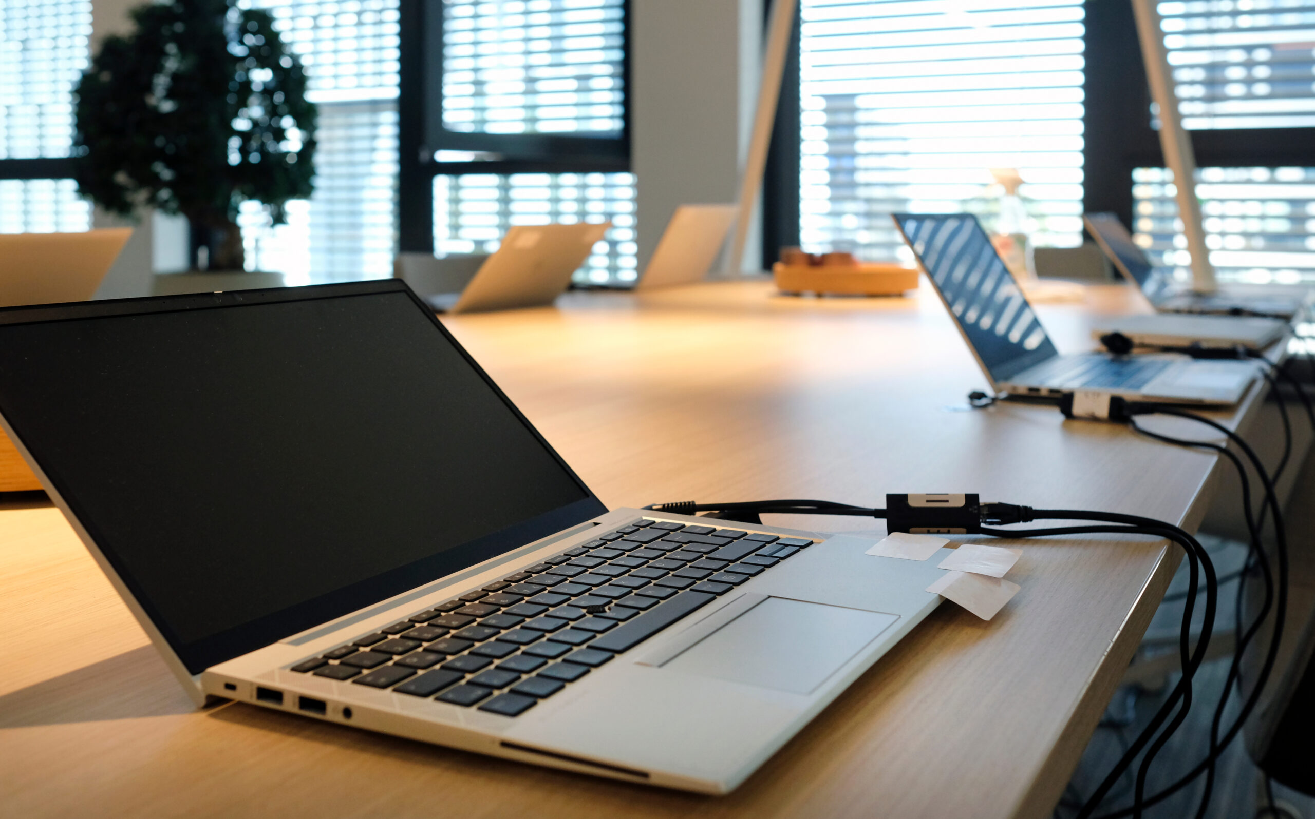 Laptop on a table in a co-working space Divi-About-Us-Section-Hero-Image-2