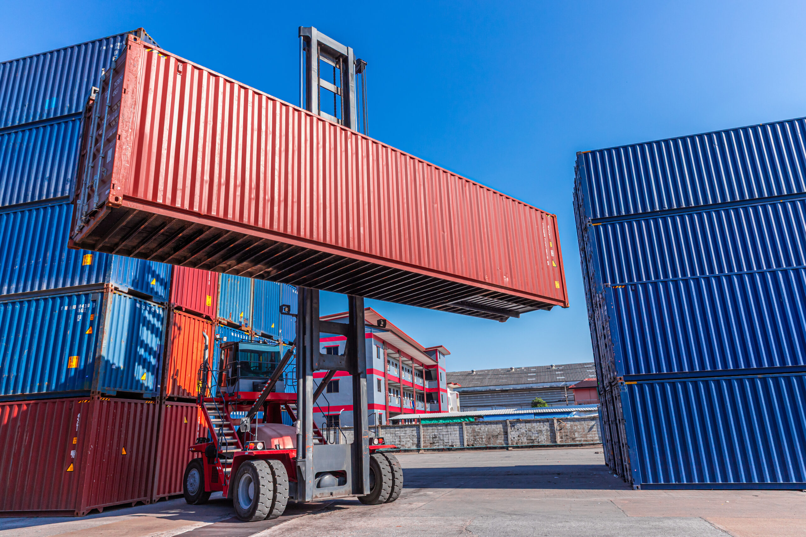 Truck forklift lifting loading heavy container cargo box at port container yard shipping logistics Divi-About-Us-Section-Hero-Image-2